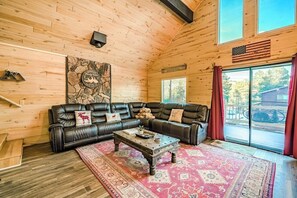 Ein gemütliches Blockhaus-Interieur mit einem ledernen Ecksofa, einem Couchtisch, einem großen Teppich und einem Wandgemälde.