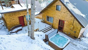 A wooden cabin with a hot tub, a red door, and a deck. - Near Town W/ Scenic Deck, Hot tub, Free WiFi, Full Kitchen & More (South Fork)
