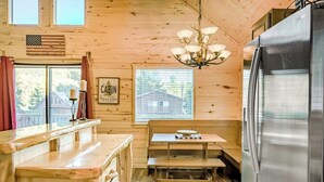 A wooden cabin interior with a kitchen area, a bench, a chandelier, and a refrigerator. - Near Town W/ Scenic Deck, Hot tub, Free WiFi, Full Kitchen & More (South Fork)