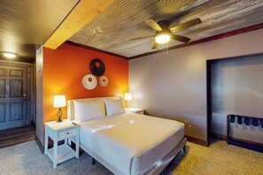 A hotel room with a bed, nightstands, a ceiling fan, a wall clock, and a door. - Mountain View Home w/ jetted tub, air hockey, foosball near Wolf Creek (Del Norte)