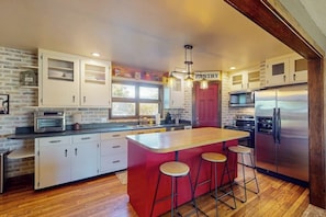 A kitchen with a central island, bar stools, a refrigerator, and a pantry cabinet. - Mountain View Home w/ jetted tub, air hockey, foosball near Wolf Creek (Del Norte)