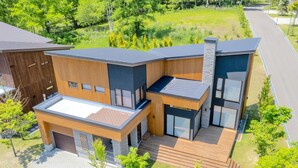 A modern two-story house with a flat roof, large windows, and a wooden exterior. - Mineta - Rusutsu Chalets (Rusutsu)