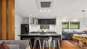 A modern kitchen with a central island, bar stools, and a dining area with yellow chairs. - Mineta - Rusutsu Chalets (Rusutsu)