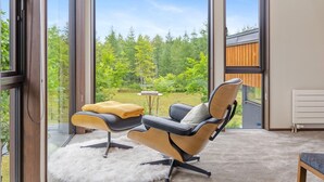 A modern room with a large sliding glass door leading to a garden, a comfortable chair, and a small table with a book. - Mineta - Rusutsu Chalets (Rusutsu)