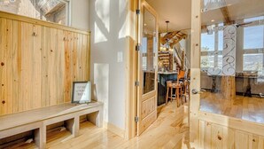 Een houten interieur met een bank, een glazen deur en een trap naar een balkon.