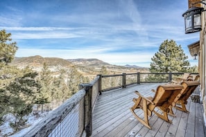 A wooden deck with outdoor seating, overlooking a mountainous landscape. - Lodge-style home with striking mountain views, fireplaces, & hot tub (South Fork)
