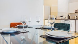 Una mesa de comedor preparada con platos, vasos y cubiertos en una cocina moderna.