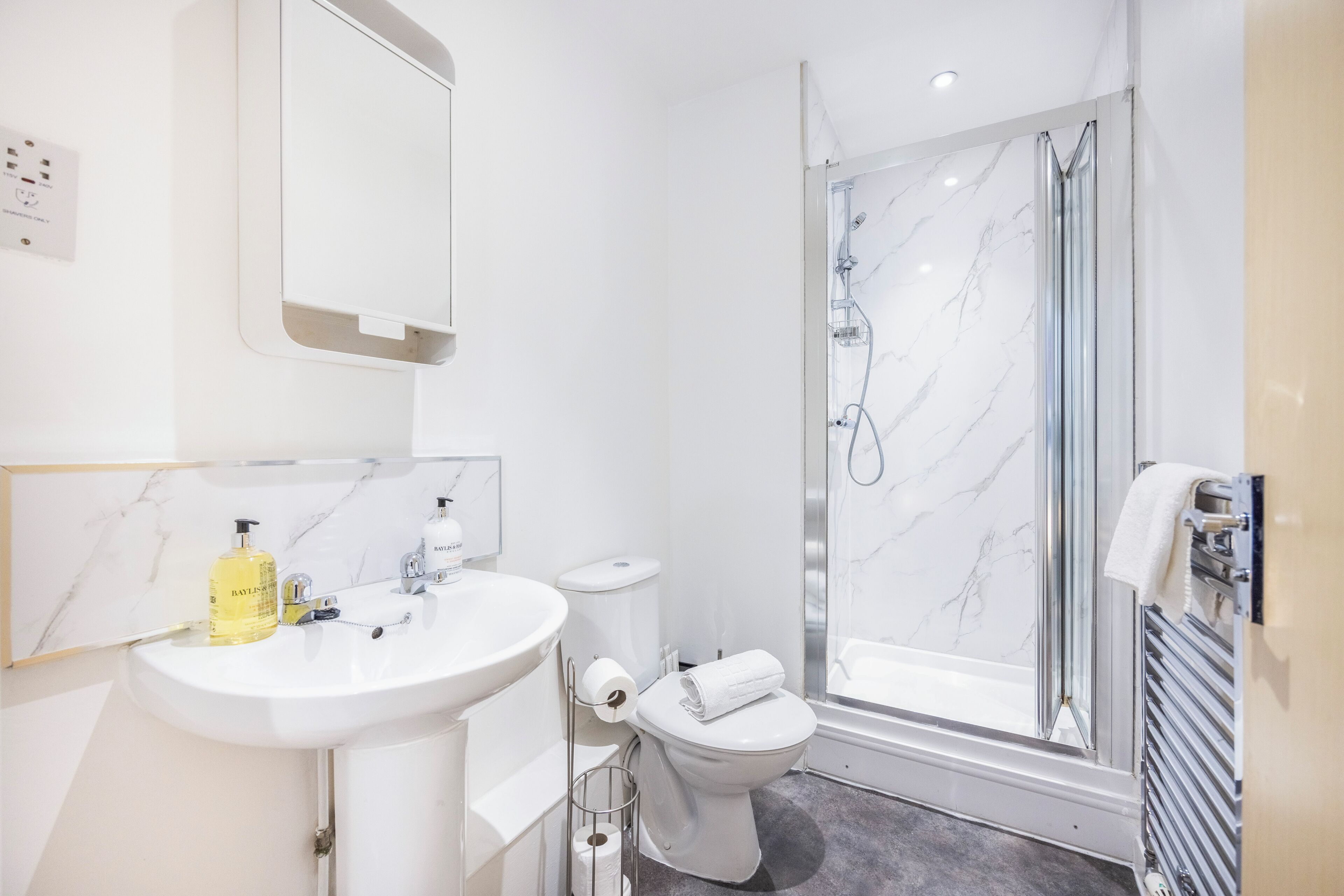 A modern bathroom with a white sink, toilet, and shower.