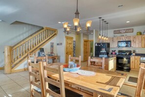 A spacious kitchen with wooden cabinets, a central island, and a dining area with wooden chairs and a table. - Dog-Friendly Golf Course Front Home w/Free WiFi, Gas Fireplace, W/D, & Gas Grill (South Fork)