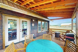 A wooden deck with a table and chairs, a covered area with a wooden ceiling, and a view of the landscape. - Mountain view modern home with open layout, gas fireplace, smart TVs, & W/D (South Fork)