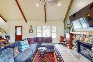 A spacious living room with a large sofa, a fireplace, and a television mounted on the wall. - Mountain view modern home with open layout, gas fireplace, smart TVs, & W/D (South Fork)