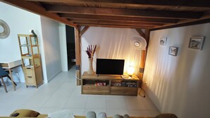 Een woonkamer met een televisie, houten meubels, een boekenkast en een kleine tafel met een lamp.