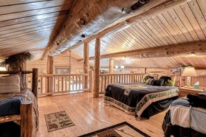 A log cabin bedroom with a large bed, wooden beams, and a balcony. - Remodeled, Dog-Friendly Cabin w/ Large Fenced Yard, WiFi & W/D - Great for ATVs (South Fork)