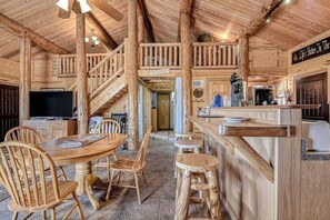 Un interior de madera con comedor, escalera y barra.