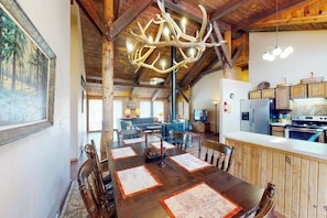 A rustic dining area with a wooden table, chairs, and a large antler chandelier. - Rustic home with mountain views, wood stove, hot tub, deck, washer/dryer (South Fork)
