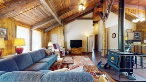 Un intérieur rustique avec un canapé, un téléviseur et un poêle à bois.