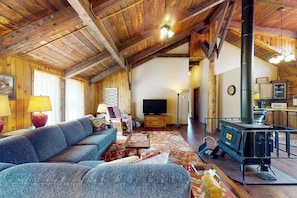 A rustic interior with a sofa, television, and a wood-burning stove. - Rustic home with mountain views, wood stove, hot tub, deck, washer/dryer (South Fork)