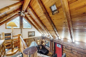 A log cabin interior with a sloped ceiling, a ceiling fan, a fireplace, a sofa, and a dining table. - Classic alpine cabin with fast WiFi, enclosed yard, deck, dogs ok (South Fork)