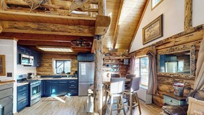 A rustic cabin interior with a kitchen, dining area, and living room.
