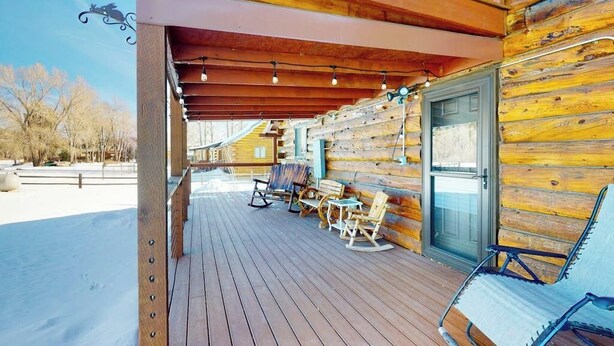 A wooden cabin with a covered porch, rocking chairs, and a door with a glass panel. - Riverfront home with river & valley views, wood stove, deck, & W/D (South Fork)