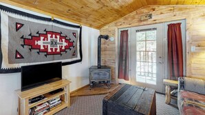 Un accogliente interno di una baita con televisore, camino, divano e libreria.