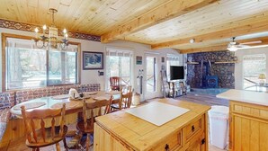 Ein Holzinnenraum mit Essbereich, Küche, Steinwand und Kamin.