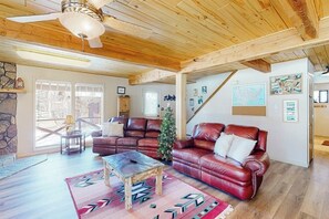 A spacious living room with a wooden ceiling, leather sofas, a coffee table, and a Christmas tree. - Charming riverfront cabin with mountain view, firepit, washer/dryer & grill (South Fork)