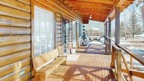 Eine Holzhütte mit einer überdachten Veranda, großen Fenstern und Blick ins Freie.