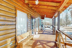 A wooden cabin with a covered porch, large windows, and a view of the outdoors. - Charming riverfront cabin with mountain view, firepit, washer/dryer & grill (South Fork)