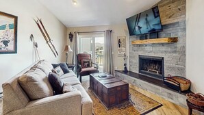 Un salon avec une cheminée, un canapé, une table basse et un téléviseur fixé au mur.
