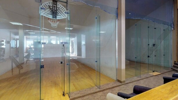 Un grand espace intérieur avec des cloisons en verre, un panier de basket et un plancher en bois.
