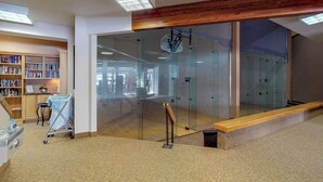 Un intérieur moderne avec un plafond en bois, une cloison en verre, une bibliothèque et un chariot.