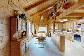 Ein Holzblockhaus-Interieur mit Essbereich, Küche und einem großen Fenster.