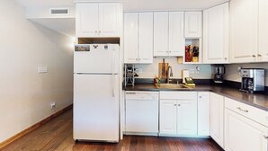 Eine Küche mit weißen Schränken, einem Kühlschrank, einem Geschirrspüler und einer Kaffeemaschine.