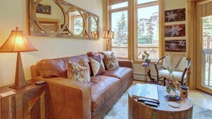 Un salon avec un canapé en cuir, une table basse et un grand miroir au mur.