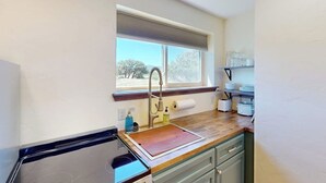 Eine kleine Küche mit Fenster, Spüle und Arbeitsplatte.