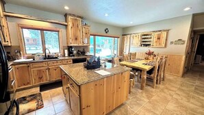 Une cuisine dotée de meubles en bois, d’un îlot central avec un comptoir en granit et d’un coin repas comprenant une table et des chaises.