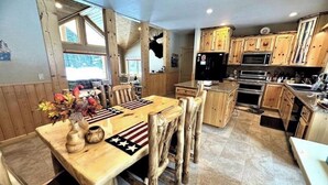 Une cuisine rustique avec des meubles de rangement en bois, une table à manger avec des chaises et un réfrigérateur.