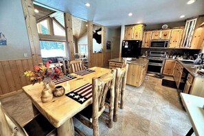 Eine rustikale Küche mit Holzschnitzhäuschen, einem Esstisch mit Stühlen und einem Kühlschrank.