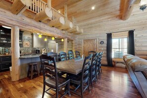 A log cabin interior with a dining area, kitchen, and a cozy seating area. - Charming cabin surrounded by trees with deck, grill, fireplace, games, & W/D (South Fork)