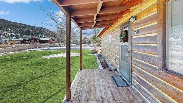 Una baita di legno con un portico, una porta con un numero e vista su un paesaggio innevato.