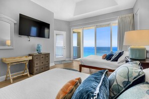 Ein Hotelzimmer mit Bett, Fernseher, Schreibtisch, Kommode und Meerblick.