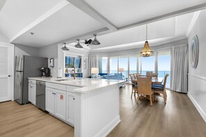 Eine moderne Küche mit einer großen Kochinsel, einem Essbereich mit Ausblick und einem Deckenventilator.