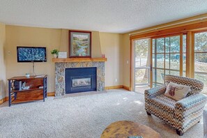 A living room with a fireplace, a television, a sofa, and a coffee table. - One Mile to Slopes with Gas Fireplace, Balcony & Shared Hot Tub/Sauna/Steam Room (Steamboat Springs)