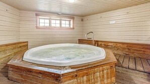 Ein Holzinnenraum mit Whirlpool, Holzbänken und einem kleinen Fenster.