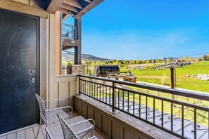 A balcony with a view of a ski lift and a grassy landscape. - Condo with two balconies, fireplace, on-site gondola, pool & three hot tubs (Steamboat Springs)