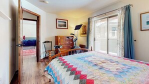 Ein Schlafzimmer mit einem großen Bett, einem Holzkleiderschrank, einem Schreibtisch mit Stuhl und einem Fenster mit Vorhängen.