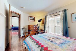 Ein Schlafzimmer mit einem großen Bett, einem Holzkleiderschrank, einem Schreibtisch mit Stuhl und einem Fenster mit Vorhängen.
