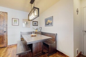 Ein Essbereich mit Holztisch und Bänken, gerahmten Bildern an der Wand und einer hängenden Leuchte.