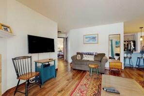 Ein Wohnzimmer mit Flachbildfernseher, einer Couch, einem Couchtisch und einem kleinen Beistelltisch.